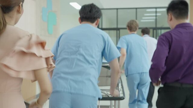 Emergency department : doctors, nurses and medical staff fush gurney - Stretcher and father, mother, son towards the operating room in modern hospital, doctor and with professional staff saving lives.
