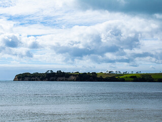 Green peninsula in the distance with ocean and a sandy shoreline in the foreground