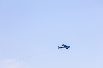 View of an advertising airplane on the sky. Plane pulling sign.