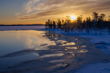 Sunrise above icy water with snow in the Pallas-Yllästunturi National Park, above the arctic...