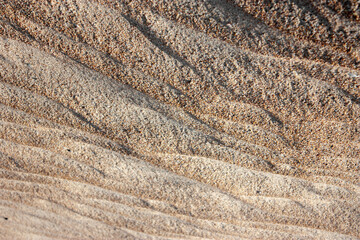 Waves on the surface of the sand, top view. The wavy surface of coastal sand. The structure of waves on sea sand. Abstract view sea sand. View from above.