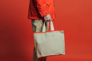 Foto op Canvas Man holding shopping bag on red background © Aleksandr Bryliaev