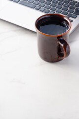 コーヒーを飲みながらノートパソコンでデスクワーク中のイメージ	
