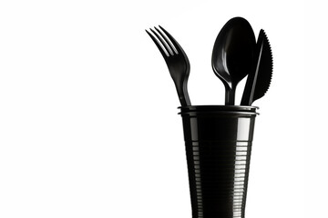 Disposable black plastic cup and cutlery on a white background. Ecology and recycling concept.