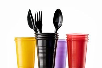 Set of multi-colored plastic cups with cutlery. Close-up, isolated on white.