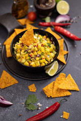 Freshly made mango salsa in a black ceramic bowl and nacho chips