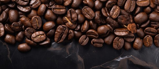 Fototapeta premium A top-down view of a pile of roasted coffee beans arranged neatly on a dark marble tabletop. The beans are various shades of brown, with a glossy appearance under the light.
