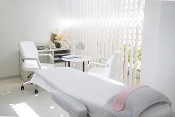 A white room with a bed, chairs, table, and a nightstand with a lamp