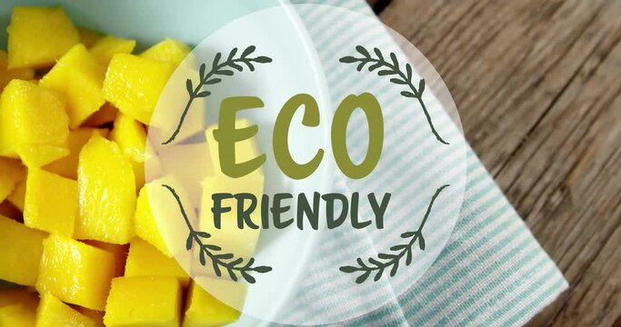 Animation of eco friendly text over mango pieces in bowl on table