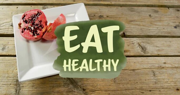 Animation of eat healthy text over pomegranate on plate on table