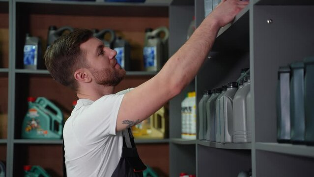 Worker on a automotive spare parts warehouse takes car oil