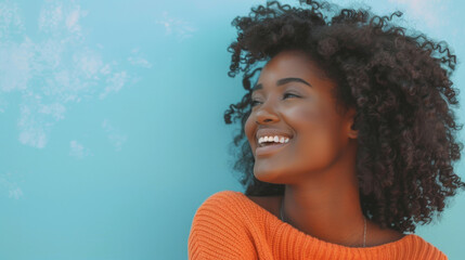 A joyful young woman in a bright orange sweater is laughing and looking away from the camera, set...
