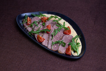 Duck breast with arugula, cherry tomatoes, and sesame seeds on a creamy sauce