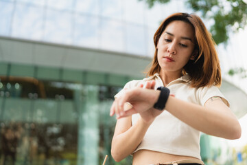 Business asian woman use smart watch standing on modern office building - 749189419