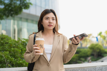 Business asian woman drinking coffee outside city building use smartphone internet connection - 749190417