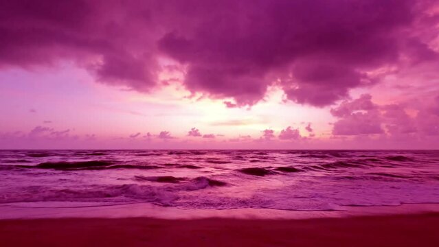 4k Slow motion sunset beach n magenta colorful sky or puple red pink cloud over sea water n calm ocean wave in tropical summer sunlight n sun ray at evening twilight coast or seashore, aerial view 