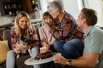 Joyous Family Celebrating Grandmothers Birthday With Cake in a Cozy Living Room
