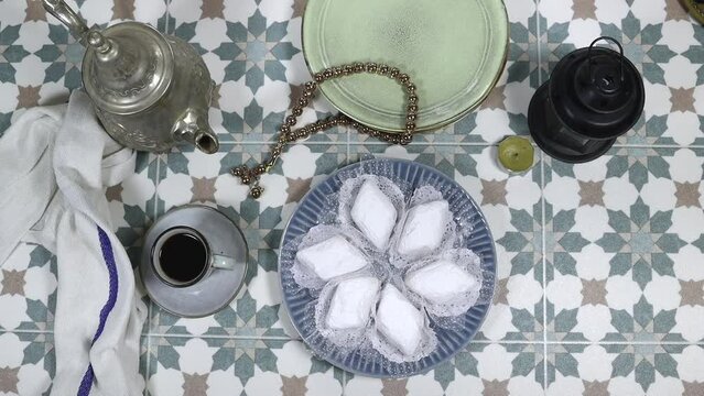 eid al fitr or aldha, ramadan concept iftar and breakfast. women drinking coffee and eating algeria cookies made from almond paste and covered with sugar powder, dates, lantern