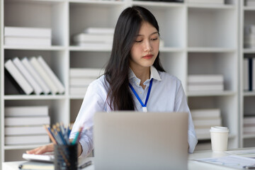 Serious businesswoman working with laptop and paperwork in office.