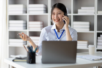 Businesswoman secretary in office using smartphone to send text messages online and talking with customers on phone.