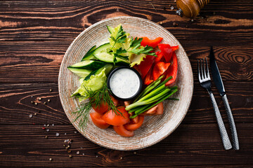 Vegetarian salad with cucumbers, lettuce, tomatoes, sweet pepper, green onion, parsley, dill and sauce.