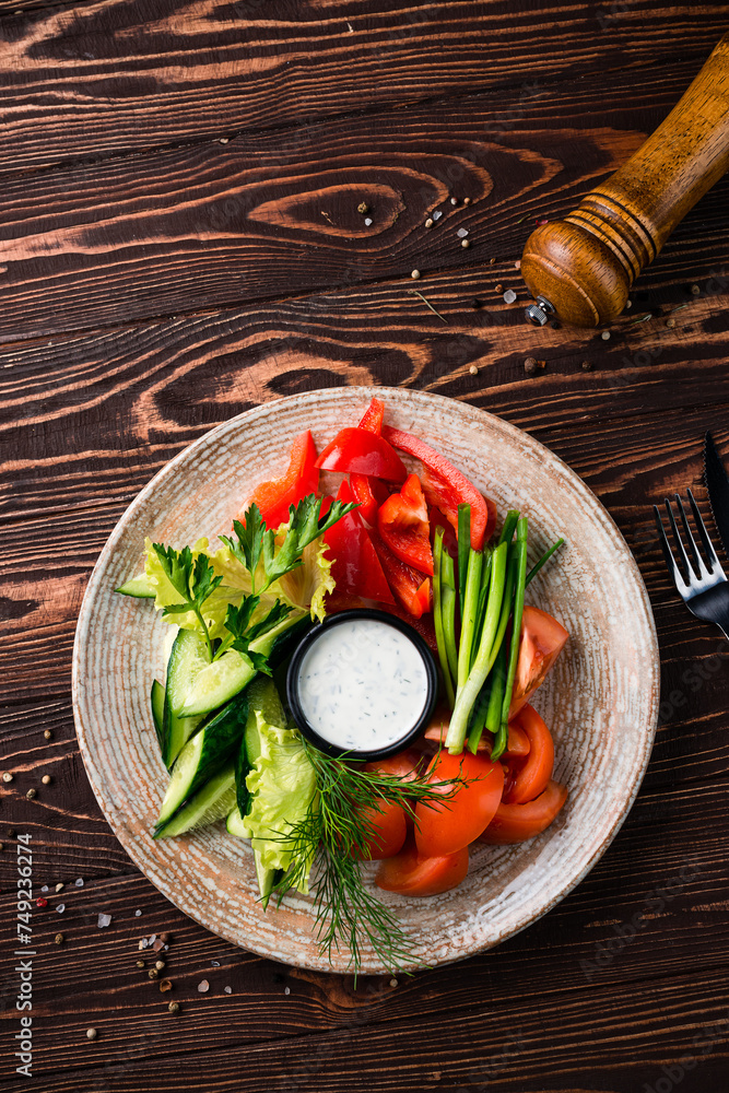 Sticker salad with cucumbers, lettuce, tomatoes, sweet pepper, green onion, parsley, dill and sauce in plate