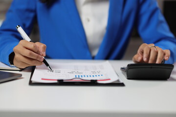 Fototapeta premium Businesswoman working overtime in office, she is analyzing financial figures data chart in business report document.