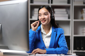 Young Asian female telephone operator working with computer in office and talking with customer.