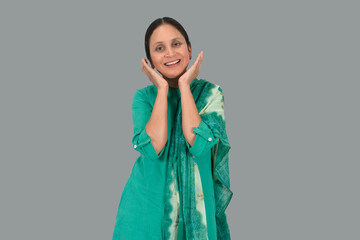 Surprised or shocked stylish girl holding hands on face or keeping hands on cheeks and looking at camera isolated on a grey background. copy space on both sides