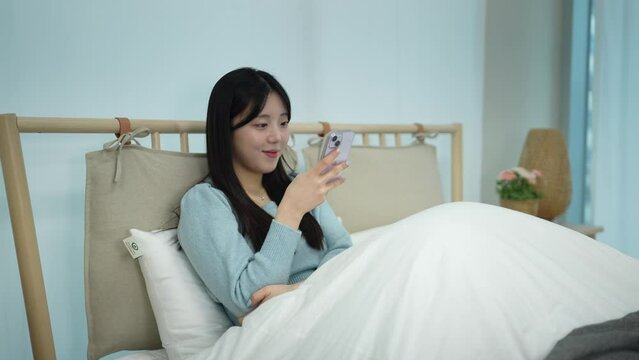 A woman using her cellphone and making a call from the bed