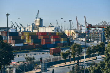 Cargo container terminal in day time. Cargo containers, gantry cranes and trucks at huge logistics enterprise