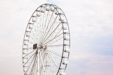 An empty Ferris wheel during the day against a white cloudy sky.