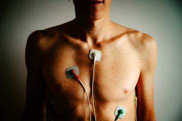 Vibrant EKG display on a young man chest, capturing the rhythm of a healthy heart under the glow of natural light.