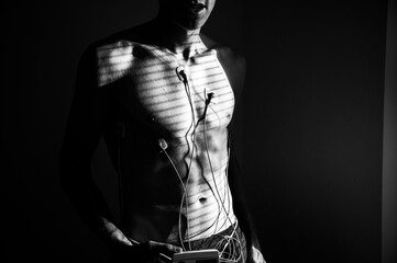 Capturing the heart's rhythm: EKG patterns on a young man, bathed in the radiance of natural daylight. Black and white photo. Edit psace