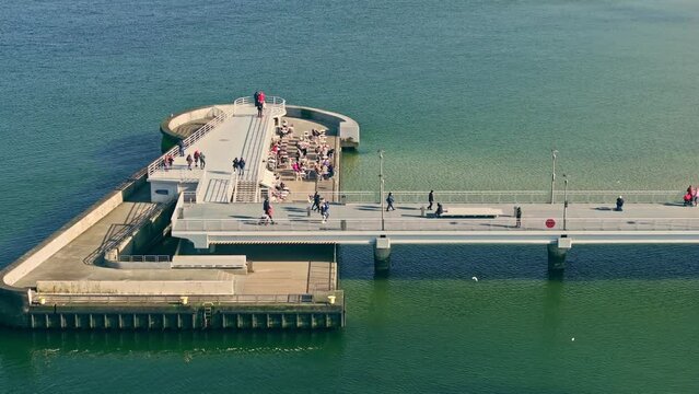 Kołobrzeg pier in a sunny winter afternoon. No waves, tourists strolling. Calm sea, clear sky.
