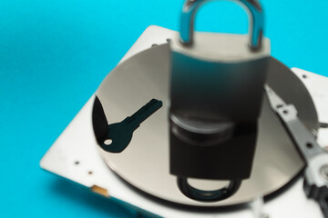 Data security concept. Cyber security concept with a padlock on hard disk. A disassembled hard drive, pad lock and key in the hands of a hacker. Blocked storage device