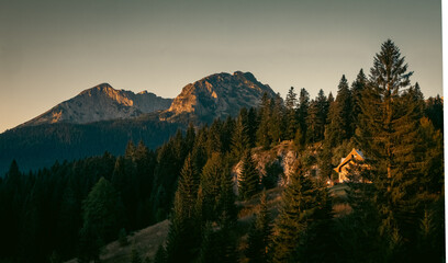 Autumn sunrise in the mountains with a house in the forest and peaks in the background, Durmitor, Montenegro