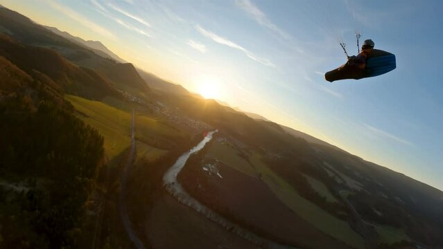 Paraglider swinging on red paragliding wing at sunset, action adrenaline adventure wingower flying