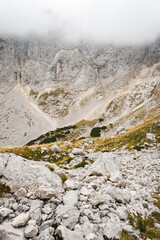 Hiking trail high in the mountains with lots of rocks and dry grass in the autumn with clouds covering peaks, Durmitor, Montenegro