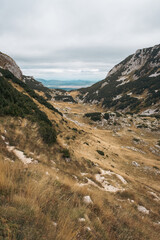 Hiking trail in the mountains with rocks and dry grass during autumn, Durmitor, Montenegro