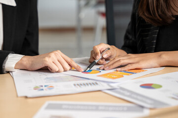 Team of professionals collaboratively analyzing financial data using charts and graphs during a...