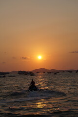 Jetskiing in the sea by the beach at sunset