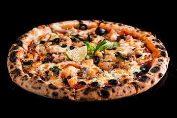 Italian pizza with salmon, onion, olives, cheese, basil, tomato sauce, lime and spices on black.