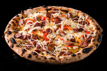 Lunch pizza with sausages, sweet peppers, tomatoes, cheese, sauerkraut and spices on black.