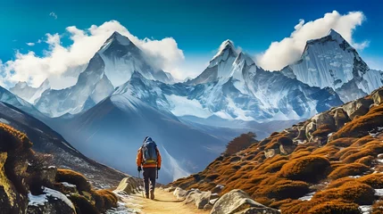 Papier Peint photo autocollant Himalaya A lone hiker traverses a rugged mountain path with snow-capped