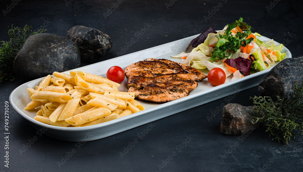 Canvas Prints penne pasta with chicken fillet and fresh vegetable salad of carrots, lettuce, cabbage and tomatoes.