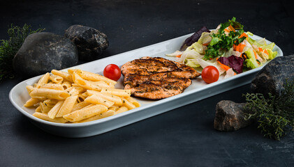 Penne pasta with chicken fillet and fresh vegetable salad of carrots, lettuce, cabbage and tomatoes.