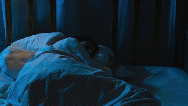 Insomniac woman tossing and turning, lying awake at night. 