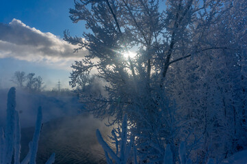 Winter landscape with fog on the river and trees in hoarfrost