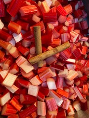 Rhubarb stems chopped red raw with cinnamon stick ready to cook background 